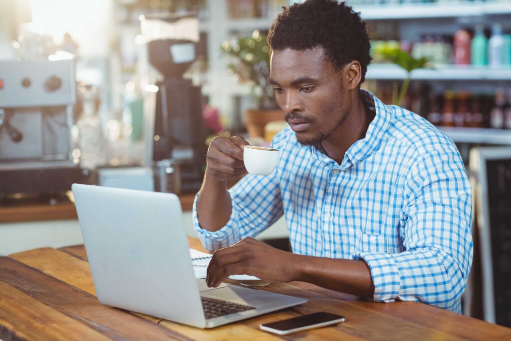 illustration shows of a man emjoying coffee at the cafe whilst working on his laptop