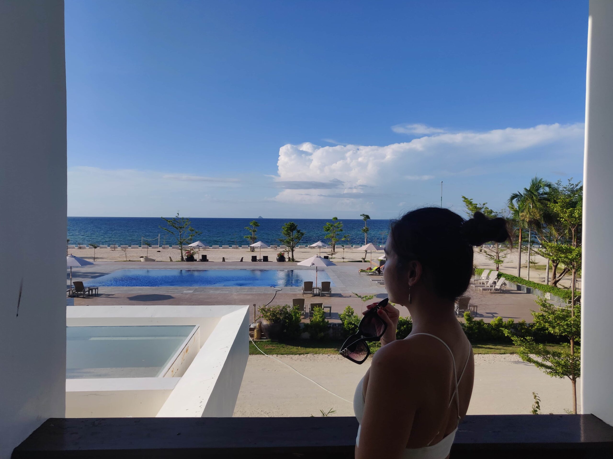 woman at the balcony staring a blue sky and turquoise sea view on a warm sunny day